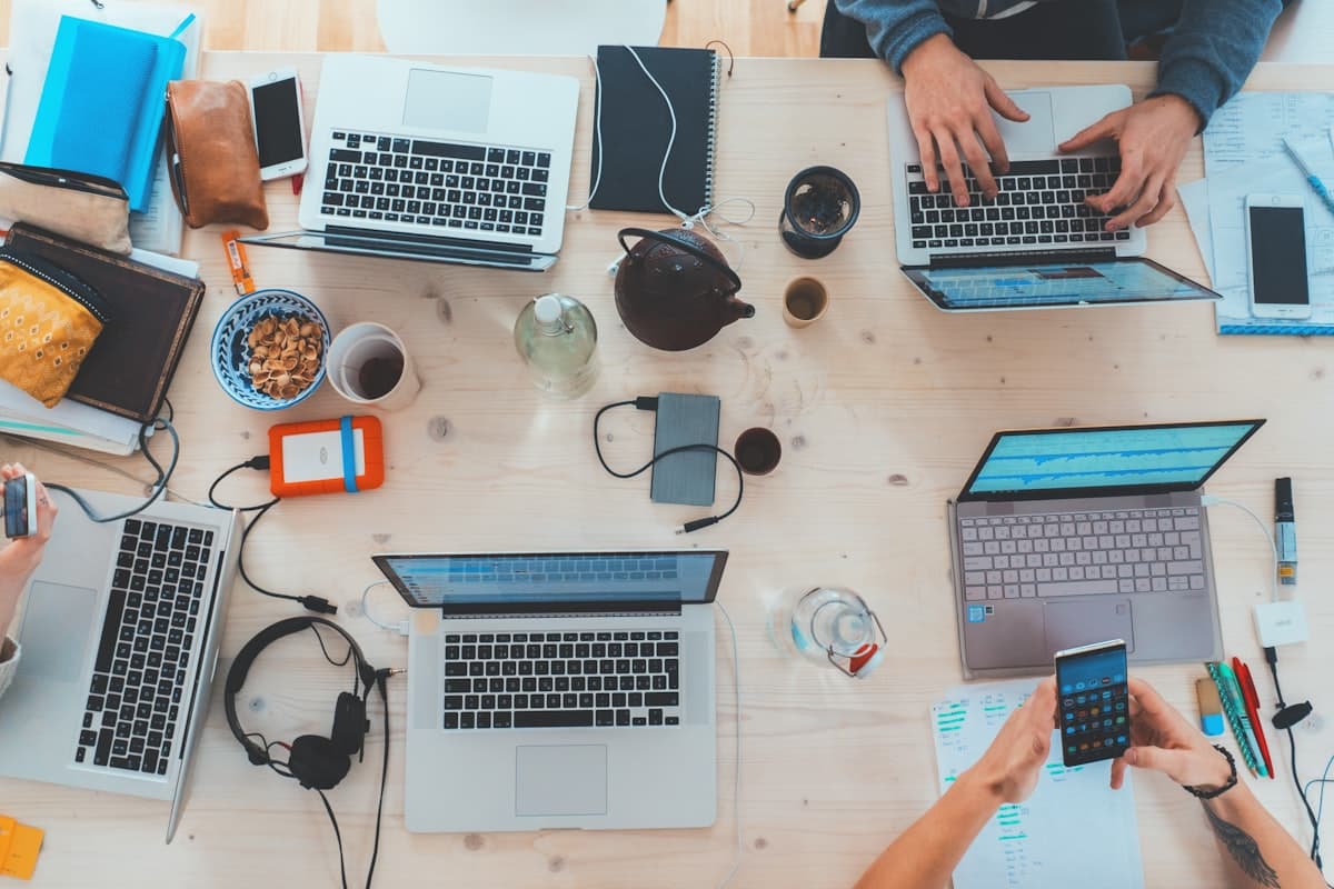 Personas trabajando en laptops sobre una mesa de madera